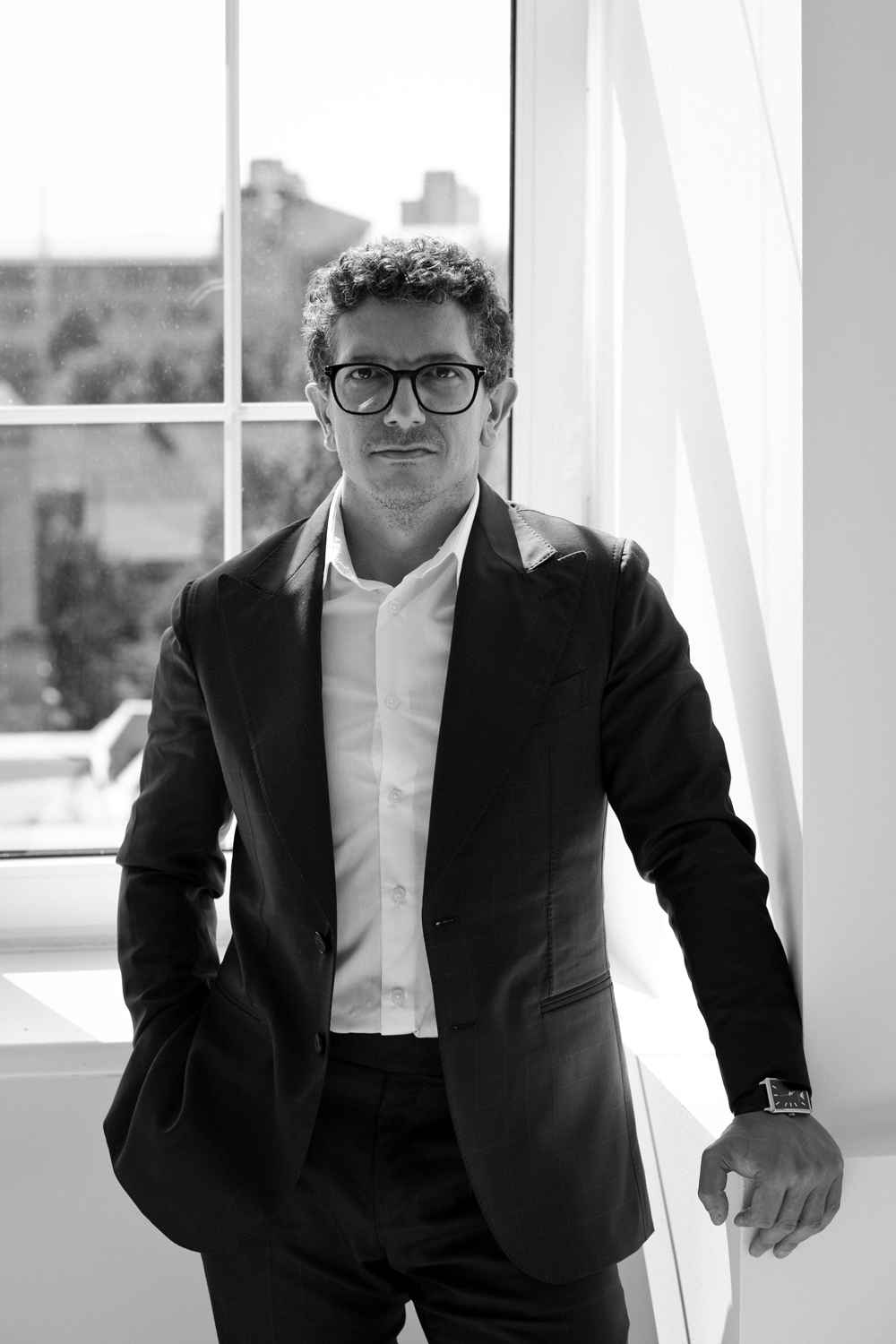 Matteo Russo standing by a window in a dark suit